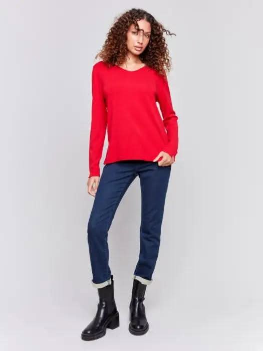 A person in a red Basic V Neck Long Sleeve Sweater by Charlie B and blue jeans stands against a plain background.