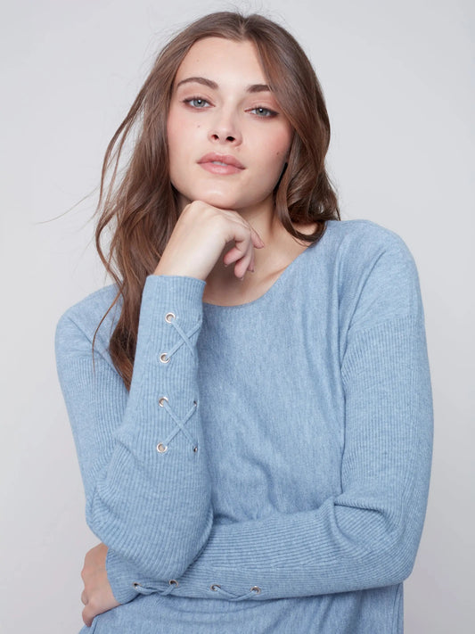 The model is wearing a high-quality light blue Charlie B Criss Cross Sleeve Detailed Sweater, showcasing functionality and style.