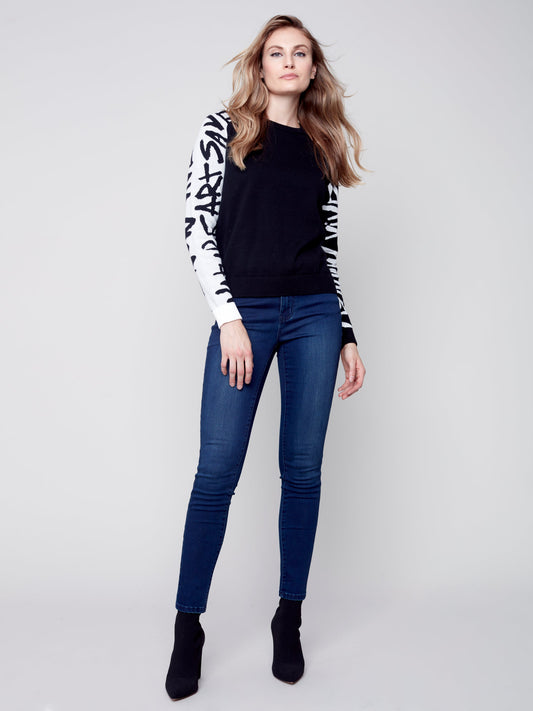A model wearing a cozy and stylish Charlie B Jacquard Art Sleeve Sweater with jeans.