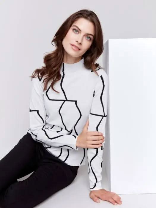 A person wearing the Reversible Jacquard Mock Neck Sweater by Charlie B, featuring black abstract patterns, stands with their back to the camera, showcasing an essential piece for any winter wardrobe.