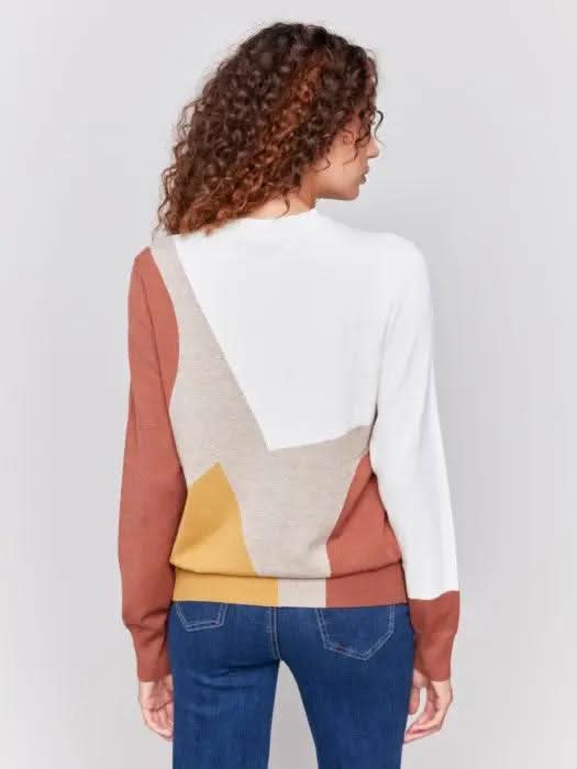 A person with curly hair is wearing the cozy and stylish Charlie B Ecru Colorblock Long Sleeve Sweater and blue jeans, standing against a plain background.