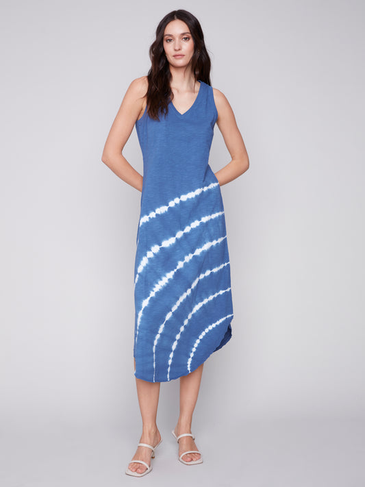 Woman posing in a Charlie B Tie Dye Elegance Dress featuring a blue and white tie-dye pattern and sleeveless design, complemented with sandals.