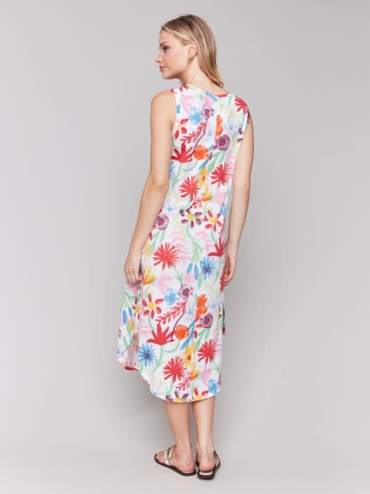 A woman wears the Charlie B Floral Printed Sleeveless Cotton Dress with white sandals against a plain light background—ideal for summer events.