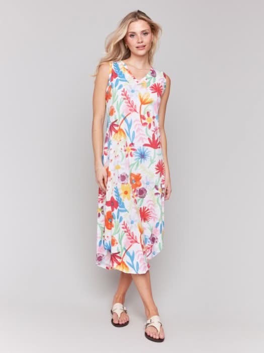 A woman wears the Charlie B Floral Printed Sleeveless Cotton Dress with white sandals against a plain light background—ideal for summer events.