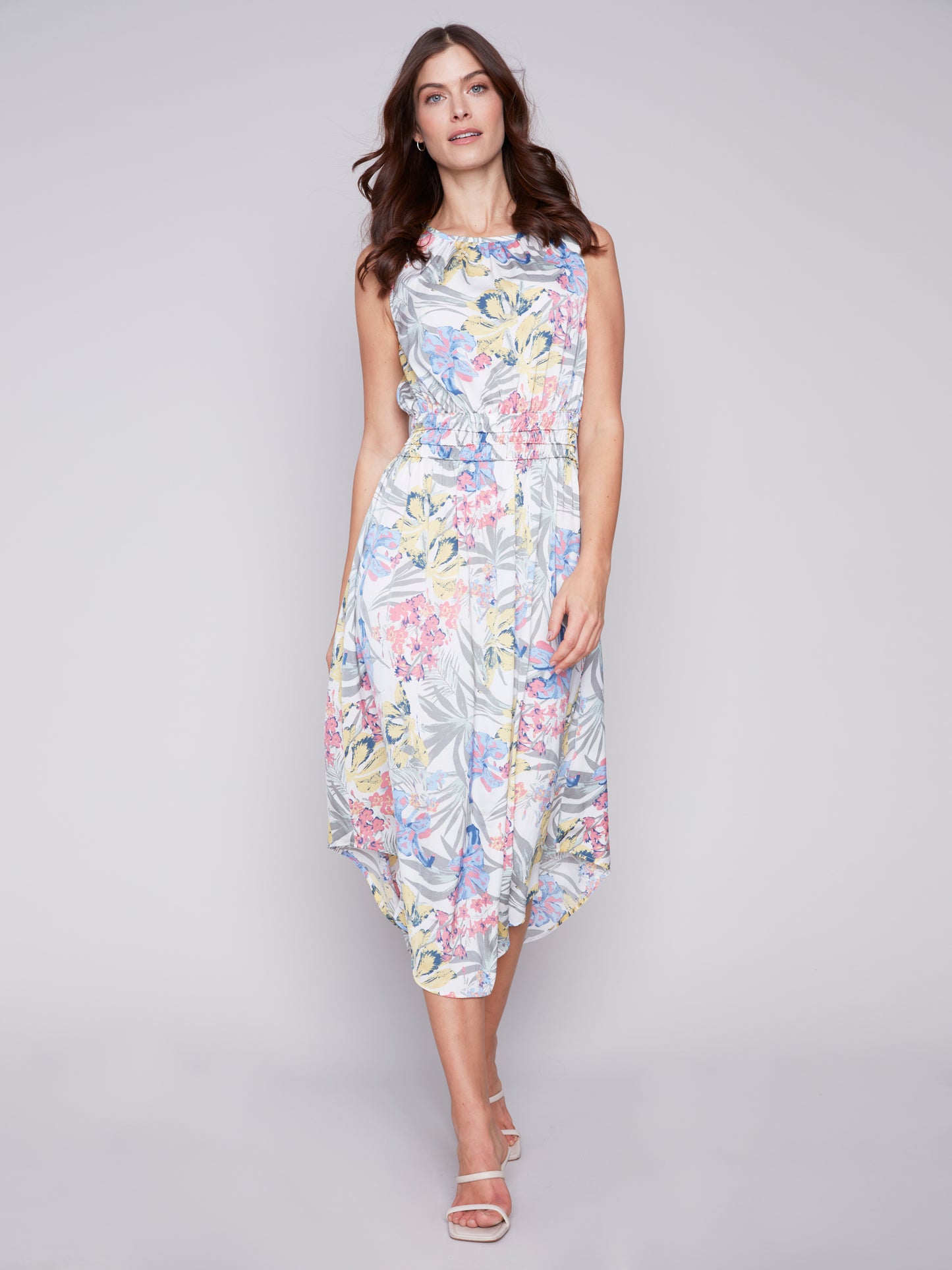 A woman in a Charlie B Petal Path Sleeveless Dress with Elastic Smocking Waist posing against a neutral background.