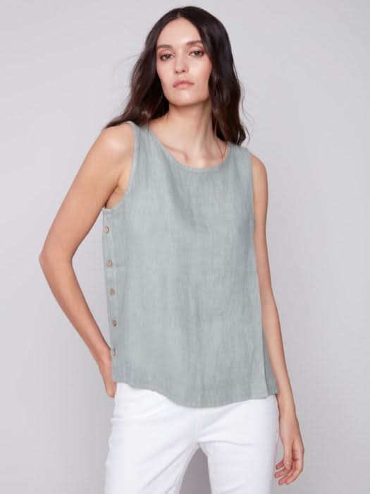 A person in a Charlie B Sleeveless Linen Top with Side Buttons and white pants stands against a plain background.