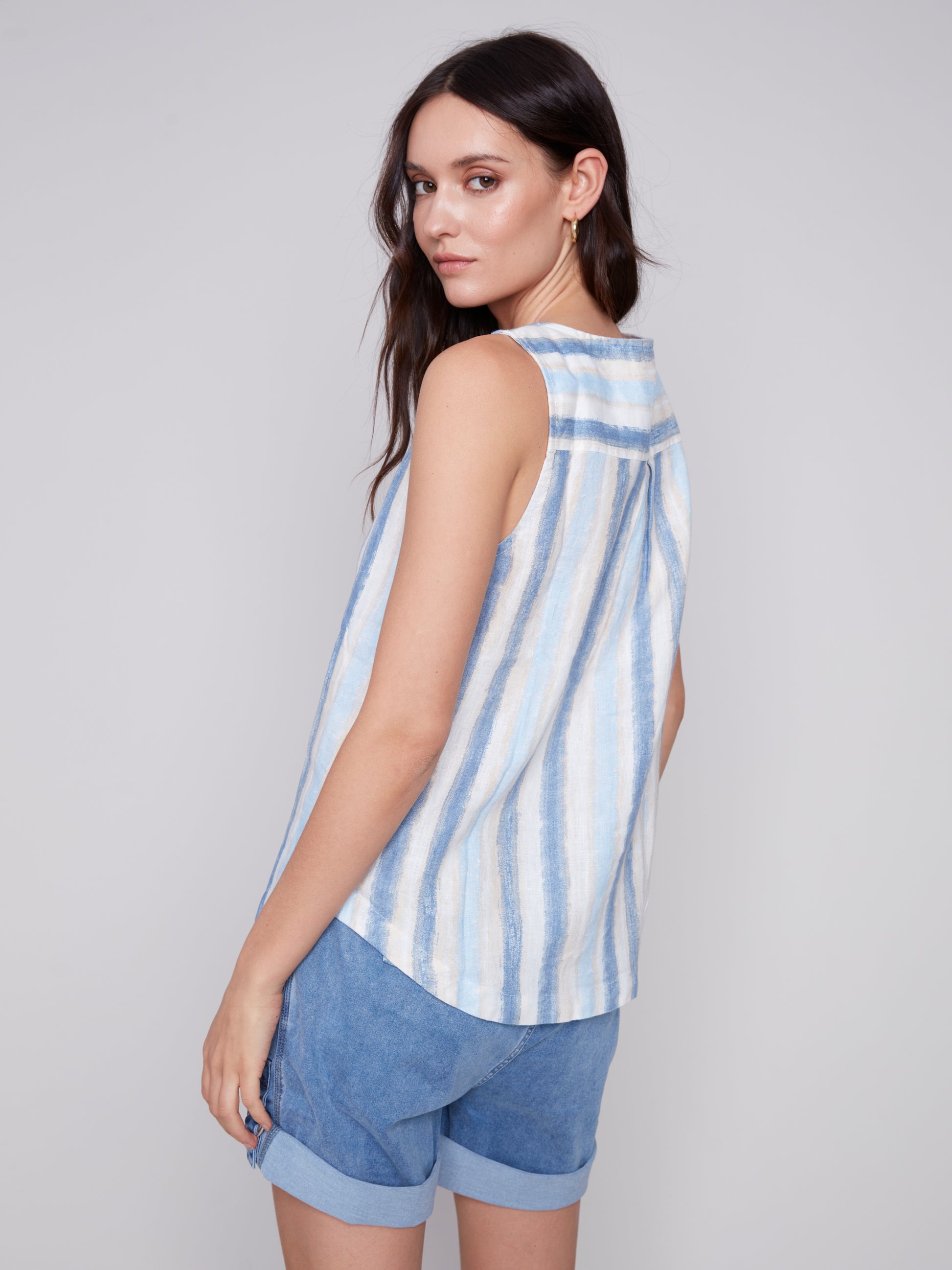 The model is wearing a stylish Charlie B Linen Top with Side Buttons in blue stripes.