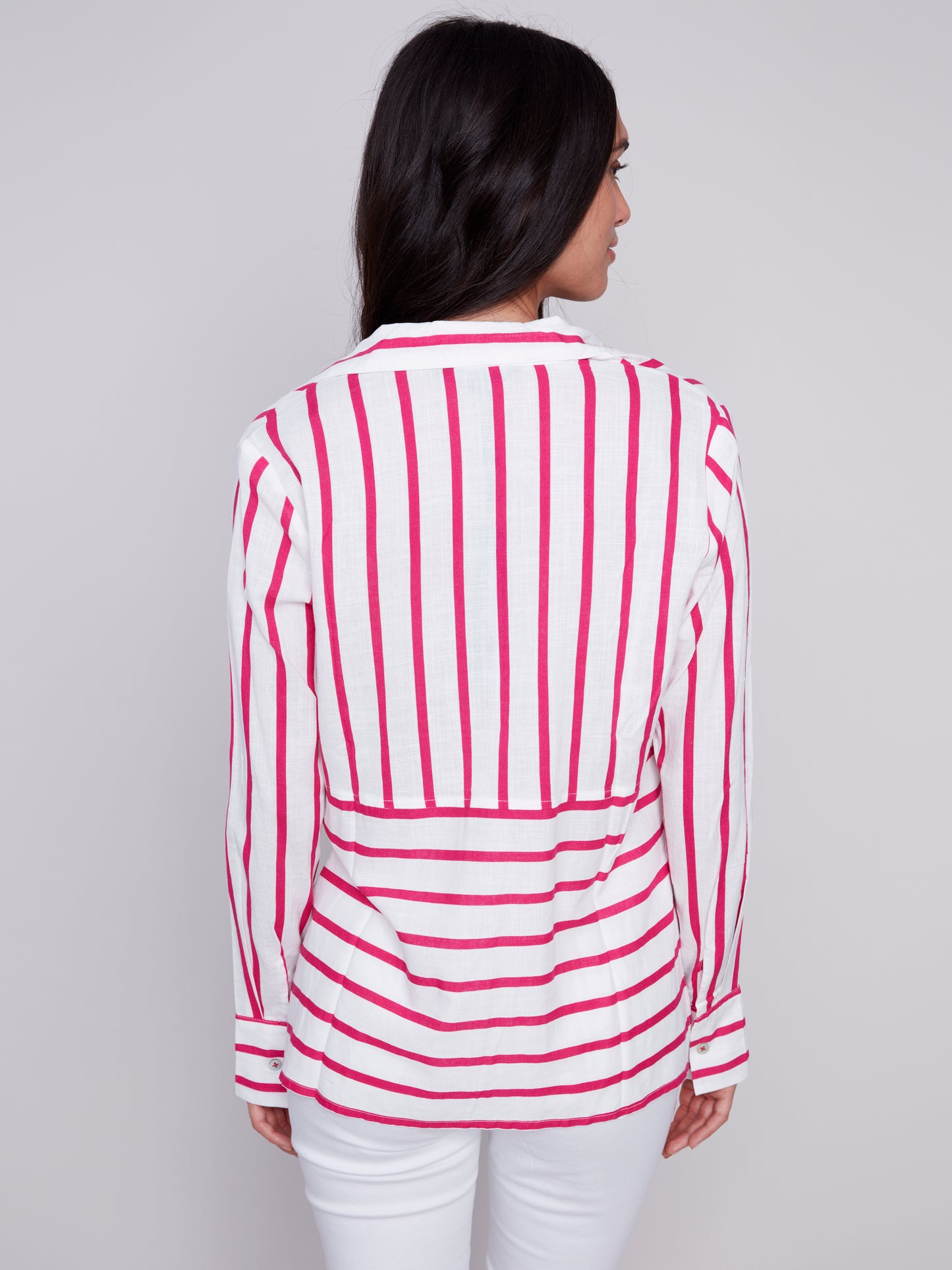 Woman wearing a Charlie B Lined Blend Striped 3/4 Button Top with white pants posing against a gray background.
