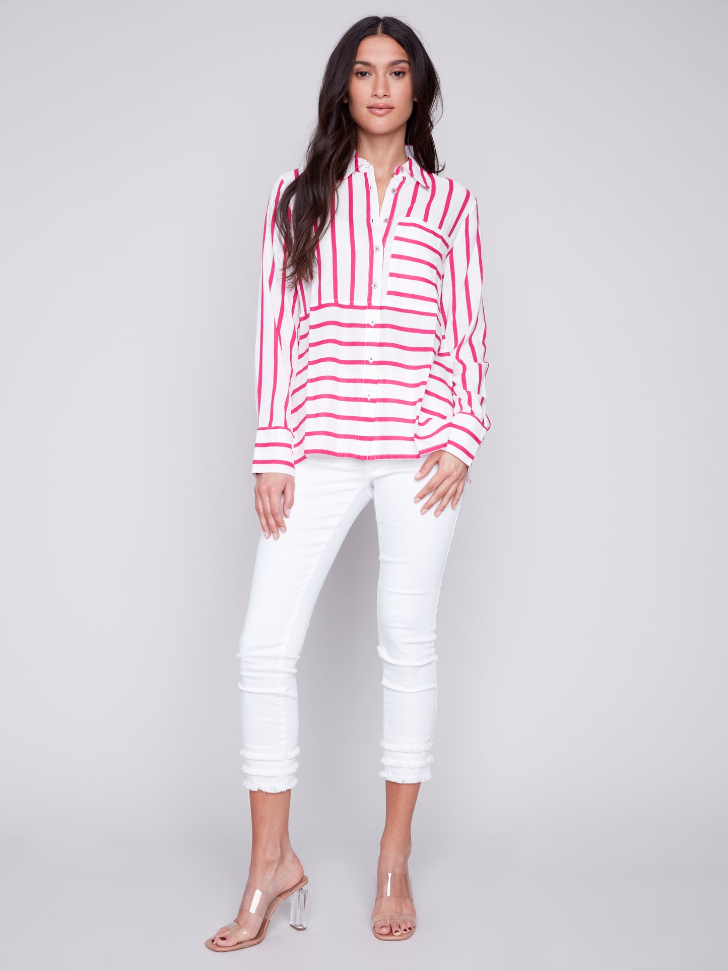 Woman wearing a Charlie B Lined Blend Striped 3/4 Button Top with white pants posing against a gray background.
