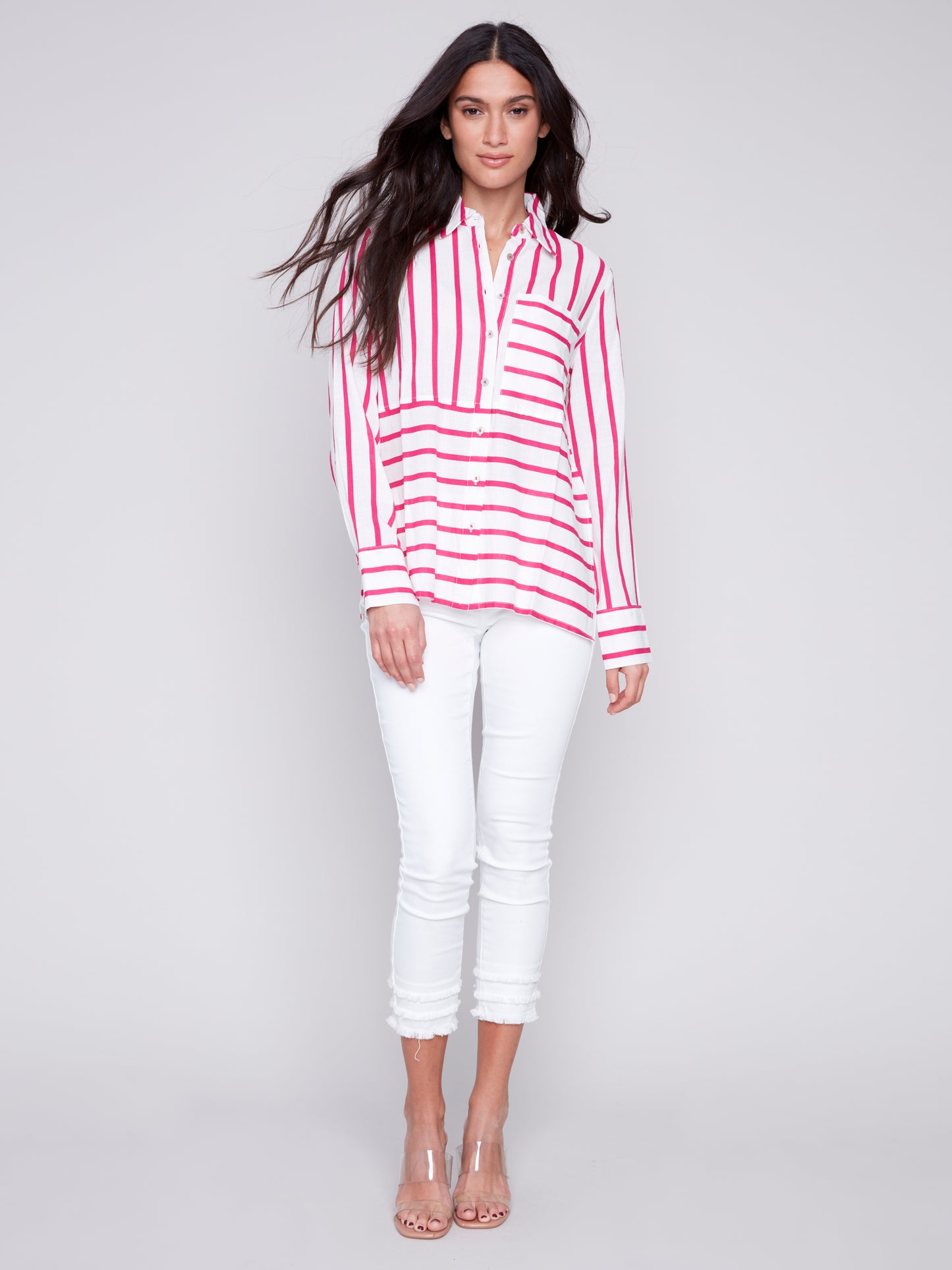 Woman wearing a Charlie B Lined Blend Striped 3/4 Button Top with white pants posing against a gray background.