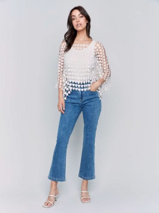 Against a plain backdrop, someone wears Charlie B's Textured Crochet Heart Top, a sheer pink heart-patterned piece layered over a white shirt.