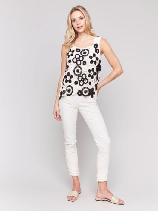 A woman wearing the Charlie B Contrast Floral Crochet Sleeveless Top with a square neck stands against a plain background.