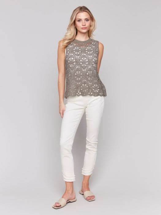 Wearing the Sleeveless Floral Cotton Crochet Top by Charlie B with white pants, the person stands gracefully against a neutral background.