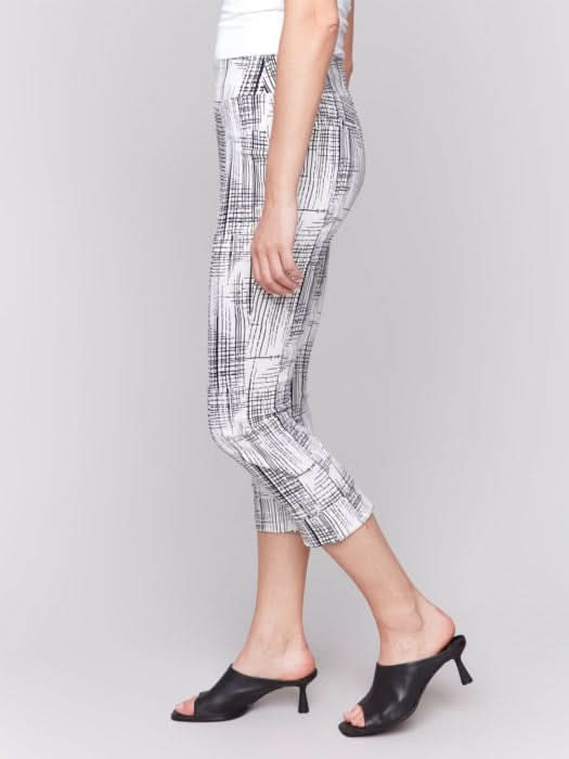 A person is wearing Charlie B's Printed Stretch Pull-On Capri Pants in black and white, offering a flattering fit. Paired with a white top and black open-toed heels, they stand against a plain background, exuding ultimate comfort for any occasion.