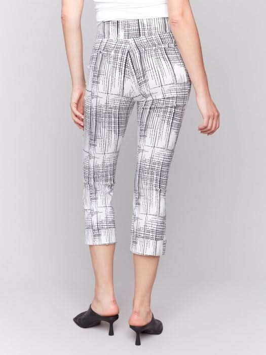 A person is wearing Charlie B's Printed Stretch Pull-On Capri Pants in black and white, offering a flattering fit. Paired with a white top and black open-toed heels, they stand against a plain background, exuding ultimate comfort for any occasion.