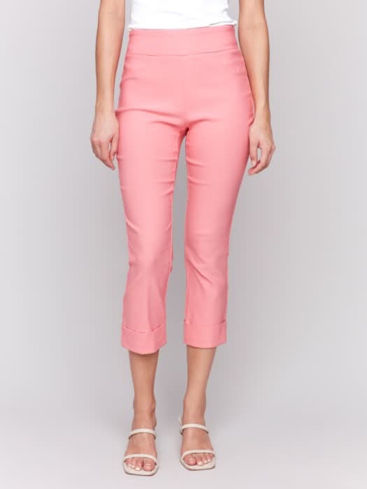 Rear view of someone wearing flattering pink Stretch Pull-On Capri Pants by Charlie B and a white top, standing in heels against a neutral background.