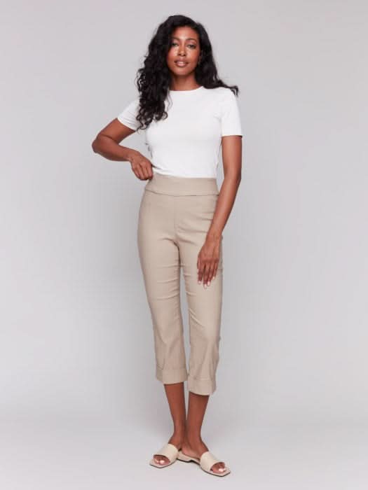 Rear view of someone wearing flattering pink Stretch Pull-On Capri Pants by Charlie B and a white top, standing in heels against a neutral background.