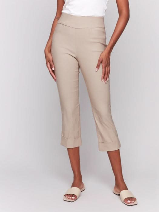 Rear view of someone wearing flattering pink Stretch Pull-On Capri Pants by Charlie B and a white top, standing in heels against a neutral background.