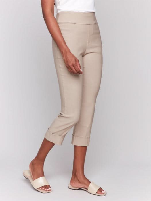Rear view of someone wearing flattering pink Stretch Pull-On Capri Pants by Charlie B and a white top, standing in heels against a neutral background.