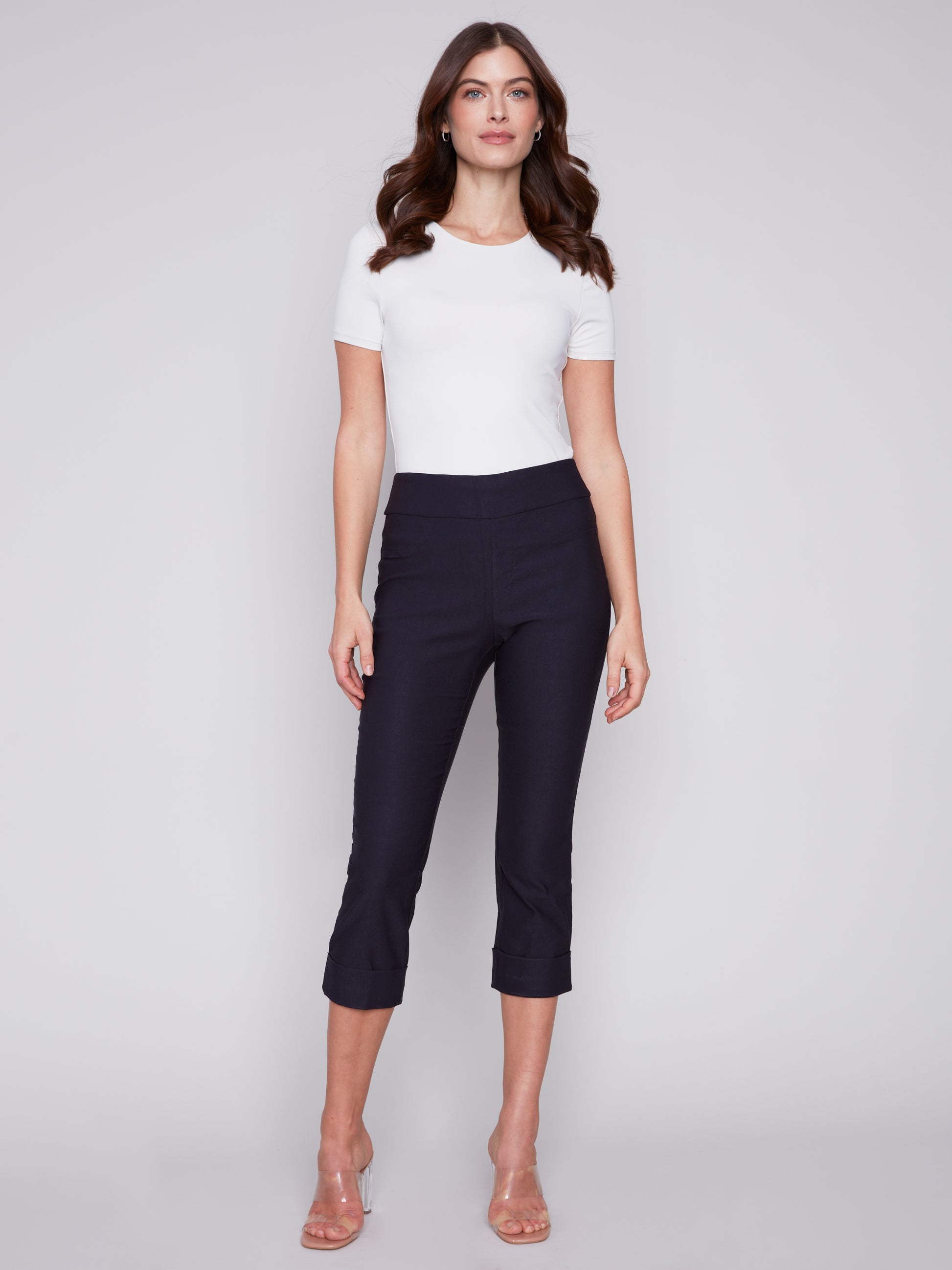 A woman showcasing her stylish Charlie B Stretch Pull-on Capri pants paired with a simple white t-shirt, perfectly balancing style and functionality.