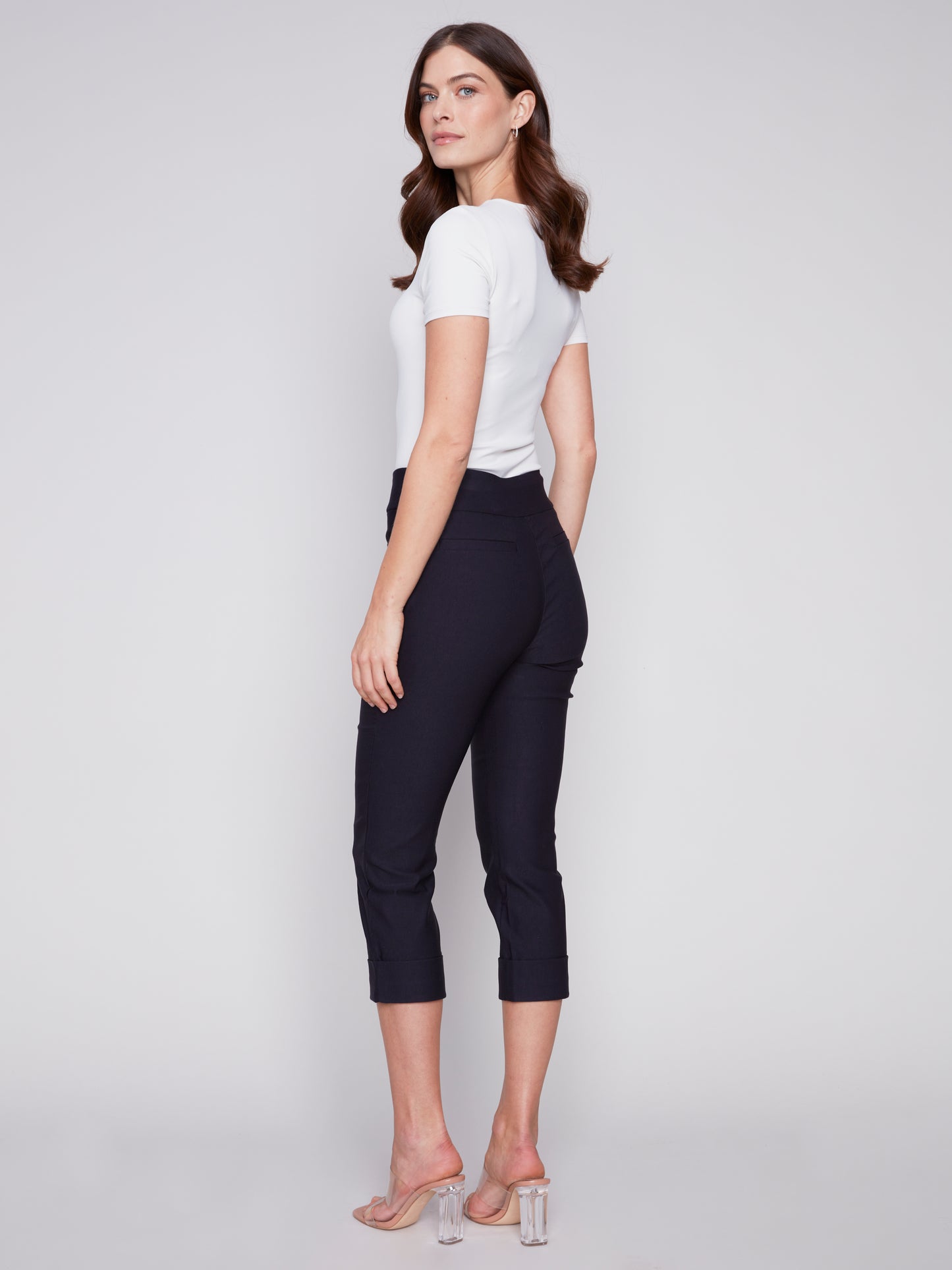 A woman showcasing her stylish Charlie B Stretch Pull-on Capri pants paired with a simple white t-shirt, perfectly balancing style and functionality.