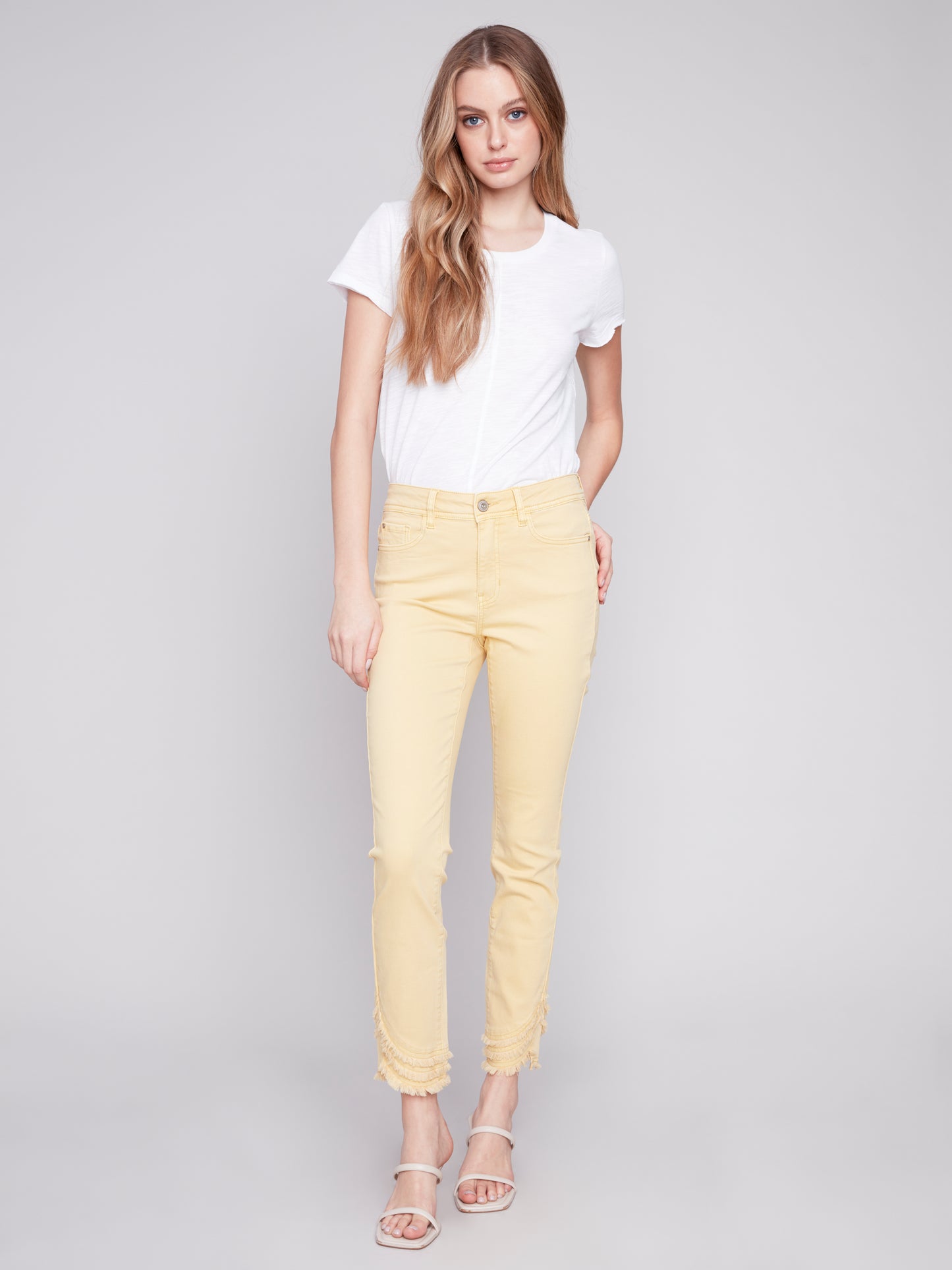 The model is wearing a cute and stylish design, combining a white t-shirt with Charlie B's Slant Fringe Ankle Pant.