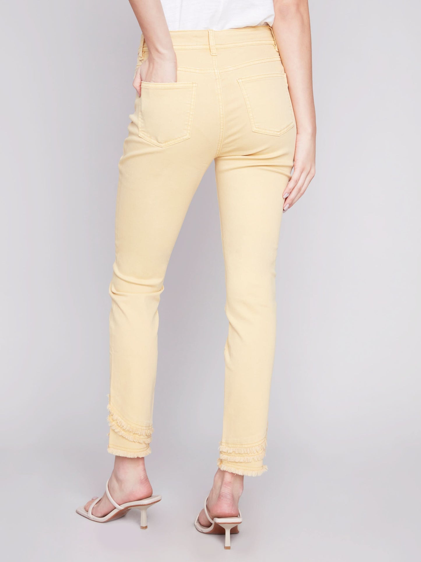The model is wearing a cute and stylish design, combining a white t-shirt with Charlie B's Slant Fringe Ankle Pant.