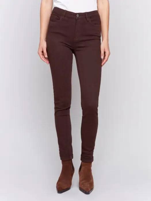 A person wearing Charlie B's brown Cuffed Hem Twill Jeans, a white top, and brown ankle boots stands against a plain background, showcasing the slimming effect and quality materials of the outfit.