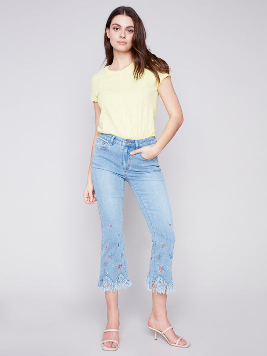 Woman modeling casual attire with Charlie B stretch denim boot cut pants and a pastel t-shirt for a perfect fit.
