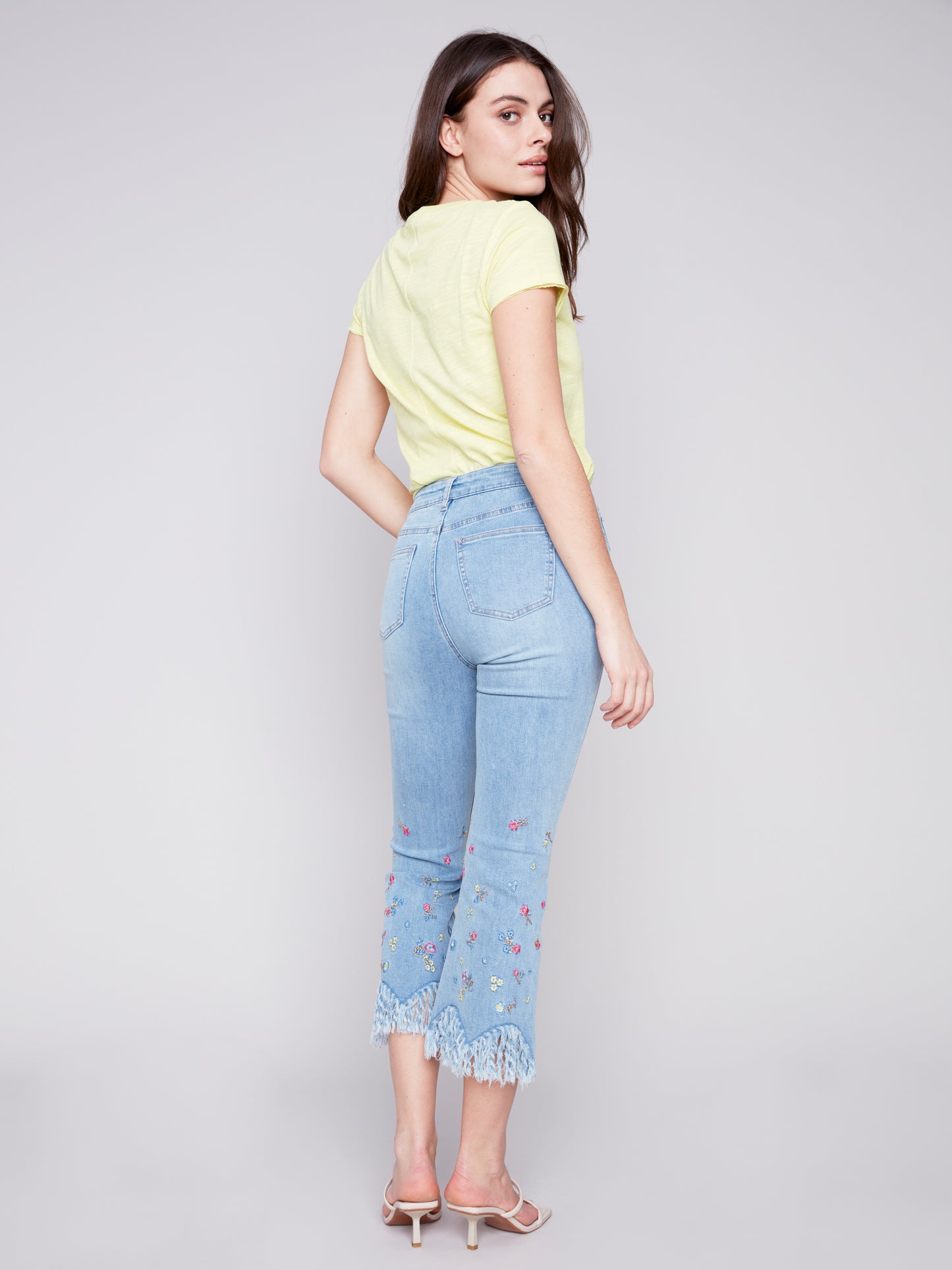 Woman modeling casual attire with Charlie B stretch denim boot cut pants and a pastel t-shirt for a perfect fit.