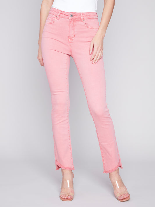 A woman wearing timeless design pink jeans with Charlie B's Asymmetrical Frayed Hem Bell Bottoms and a white top.