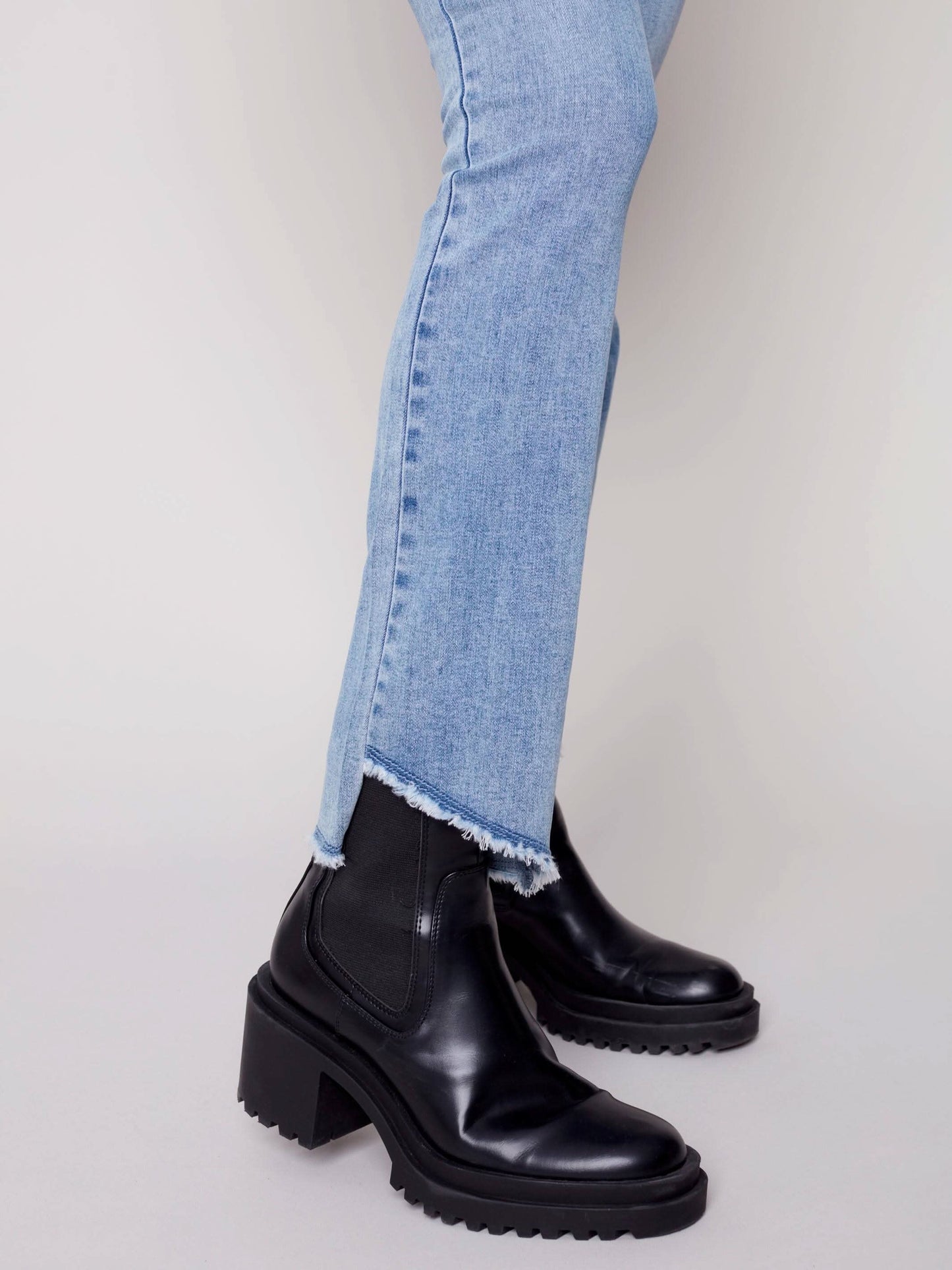 A woman in Charlie B's asymmetrical hem bootcut jeans and black Chelsea boots creates a flattering look.