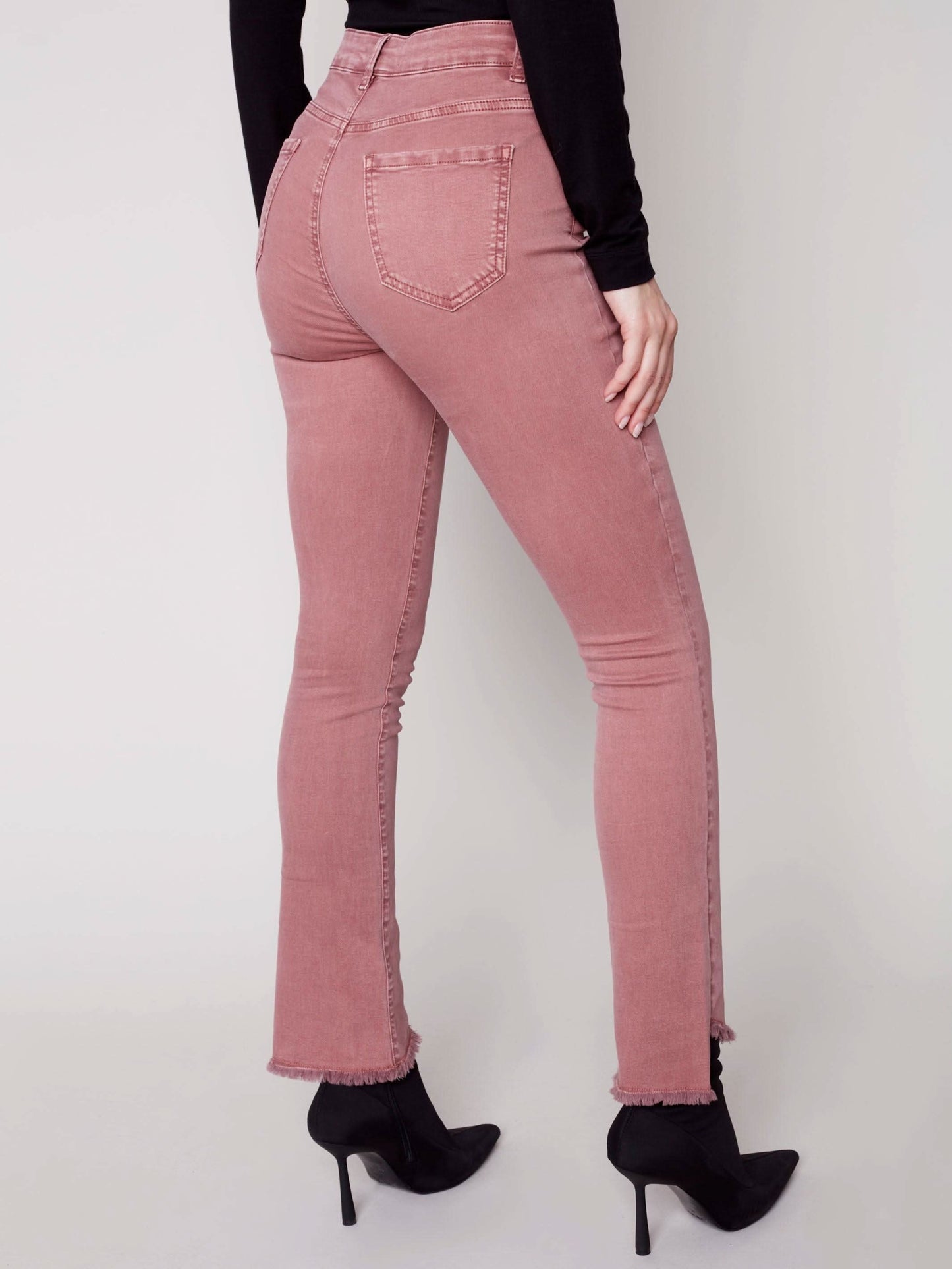 A woman in Charlie B's asymmetrical hem bootcut jeans and black Chelsea boots creates a flattering look.