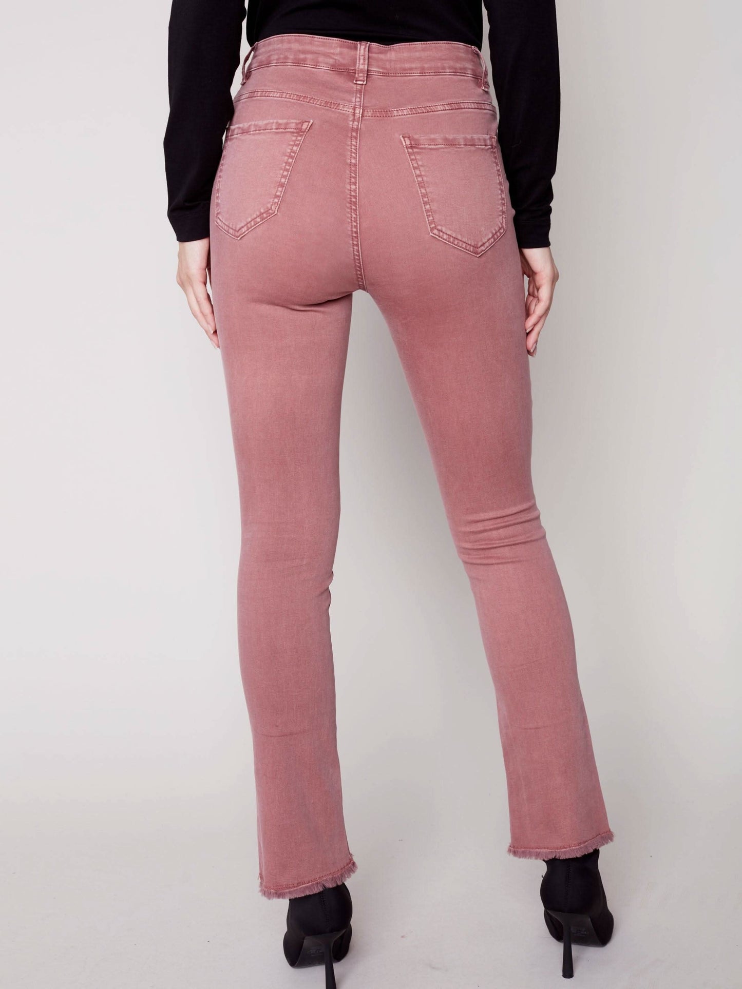 A woman in Charlie B's asymmetrical hem bootcut jeans and black Chelsea boots creates a flattering look.