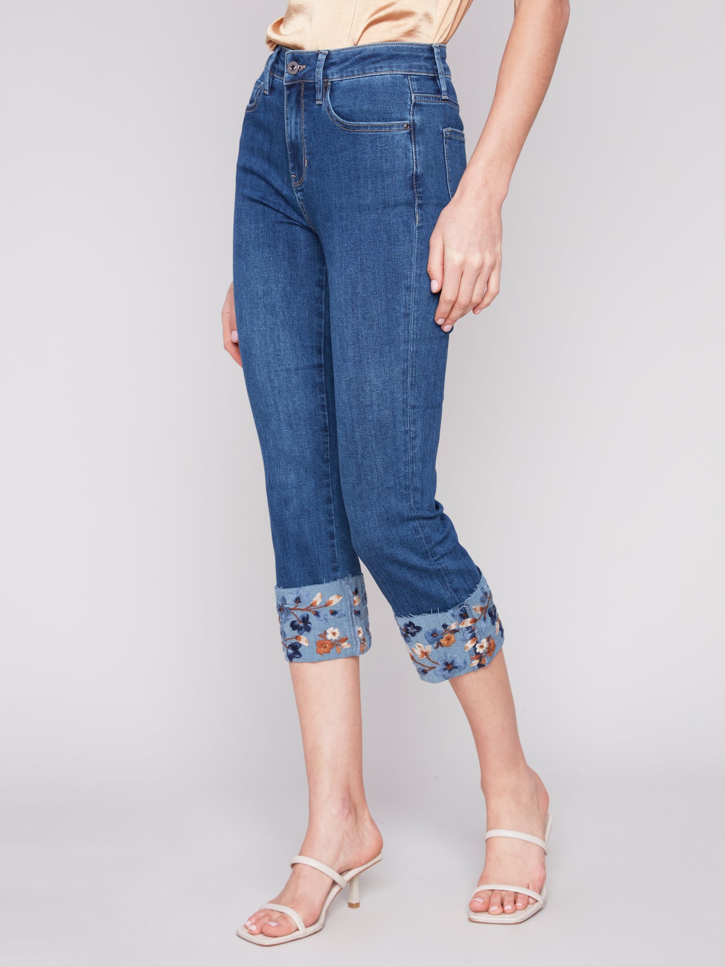 A woman wearing a pair of Charlie B stylish and versatile jeans with Embroidered Cuffed Ankle Pants.