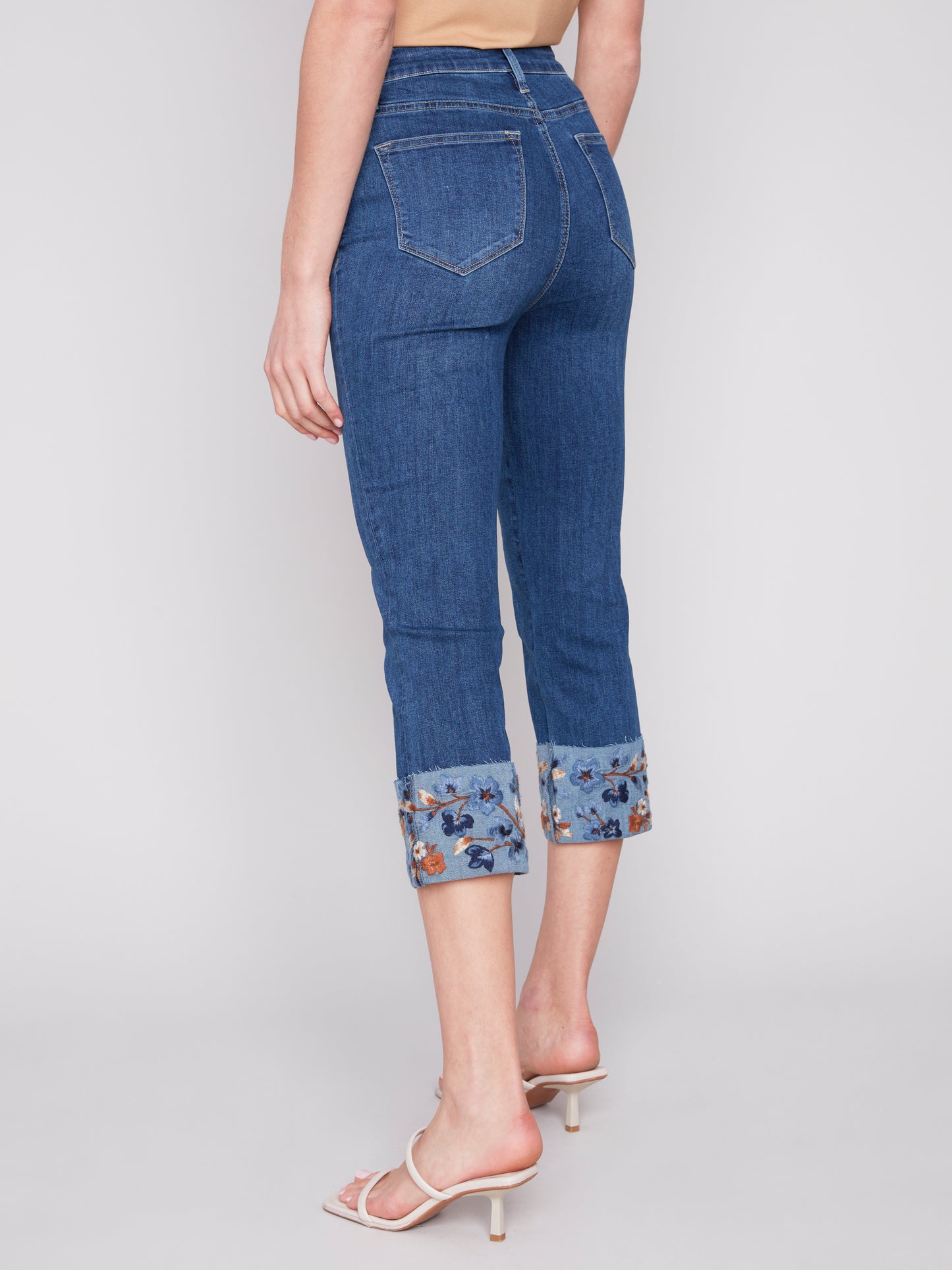 A woman wearing a pair of Charlie B stylish and versatile jeans with Embroidered Cuffed Ankle Pants.