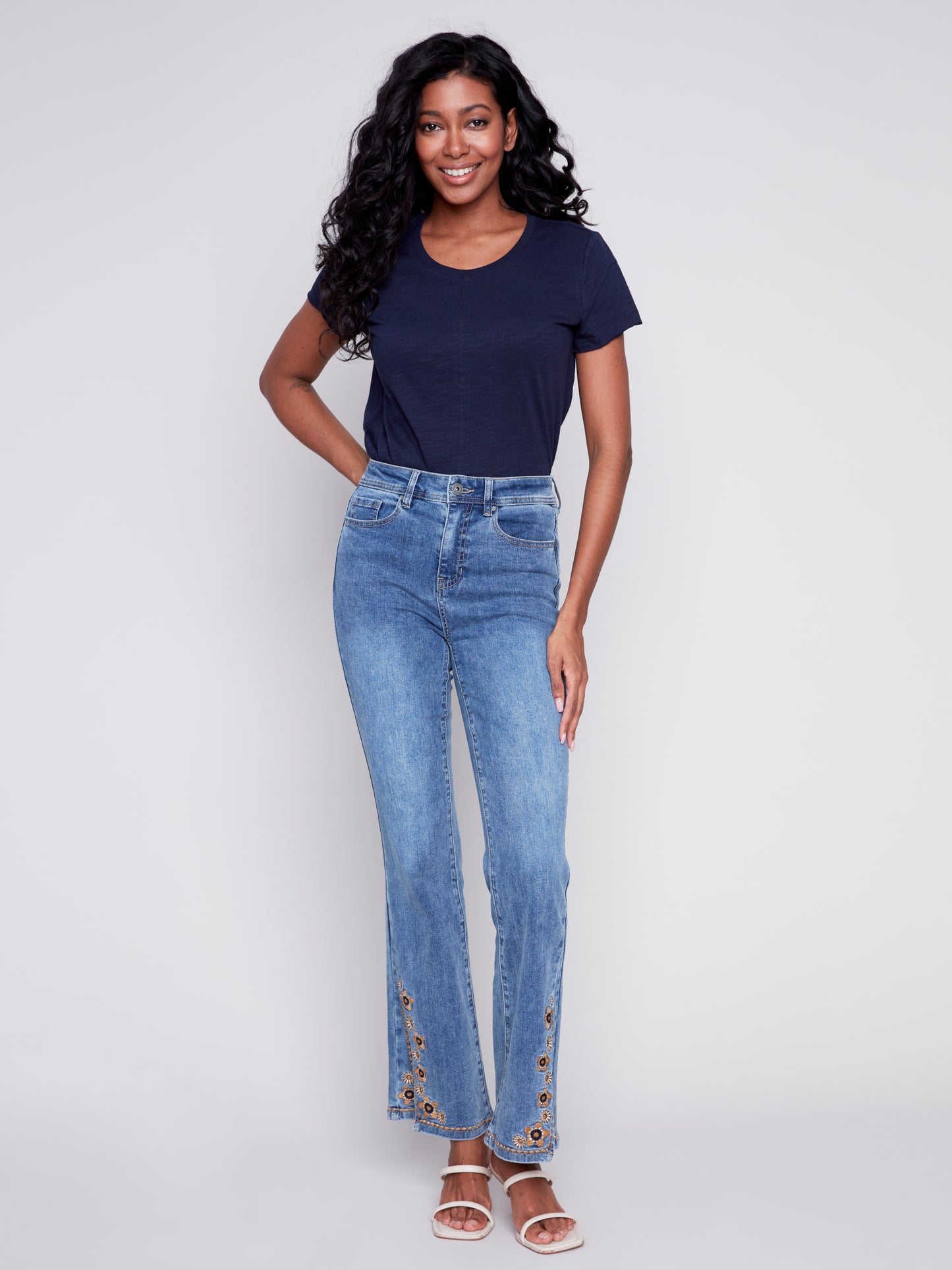 A woman exuding retro vibes in a pair of Charlie B's Slit Bell Bottom Jeans with Embroidered Slits.