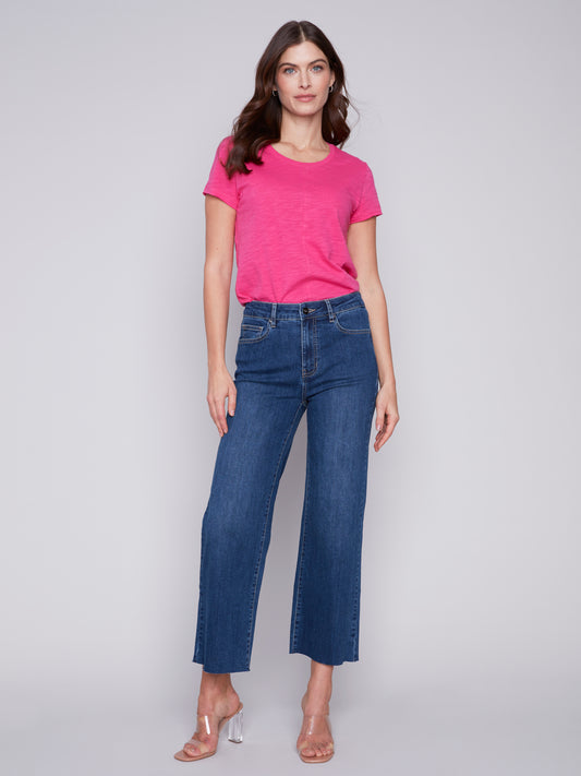 The model is wearing a pink t - shirt and Charlie B's Raw Edge Wide Leg Jeans, showcasing a timeless style.