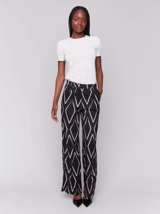 A person in a white t-shirt and Charlie B's Printed Linen-Blend Pants, featuring a chic white geometric design, stands against a gray background.