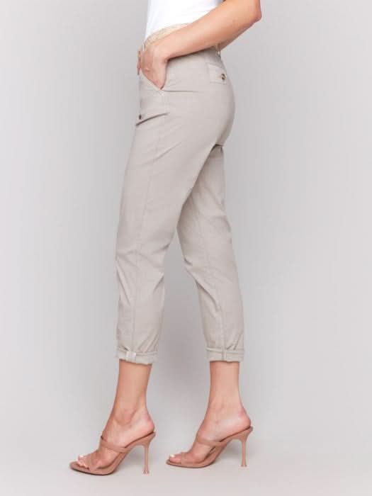 Wearing the essential Slim Pant Leg With Belt by Charlie B, a person in a white sleeveless top stands against a plain gray background, highlighting its flattering fit and slim pant leg that infuse effortless style.