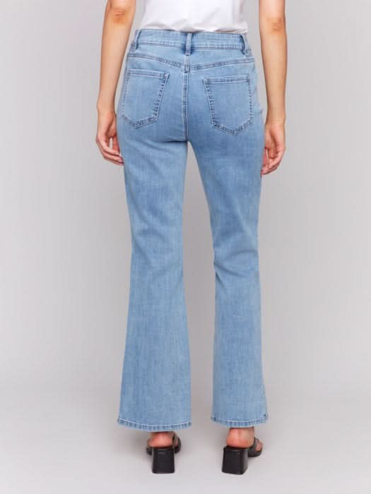 A person is seen from the back wearing Charlie B Floral Embroidered Bootcut Jeans with Front Slits and a white shirt, set against a neutral background.