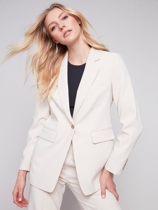 The model is wearing a Charlie B beige blazer with Rushed Back and pants made from quality fabric.