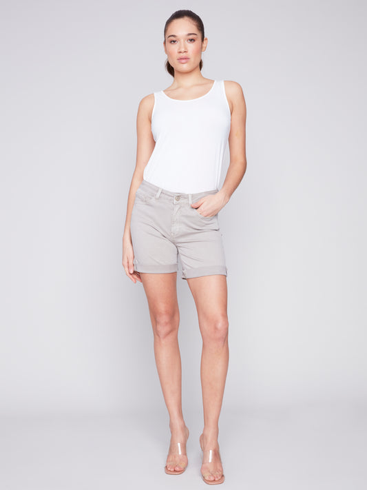 The model is wearing a white tank top and versatile Charlie B Rolled Up Cuff Shorts.