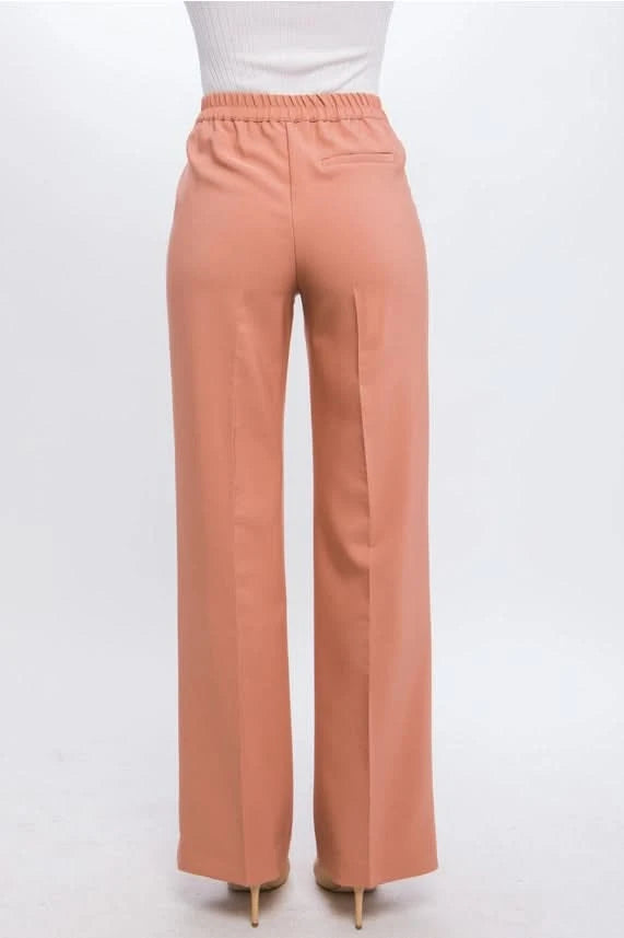A person wearing Vanilla Monkey Dress Pant with Elastic Back in bright green and black pointed-toe shoes. The background is plain white.