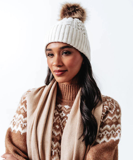A woman wearing an Echo New York Recycled Wishbone Cable Pom Hat.