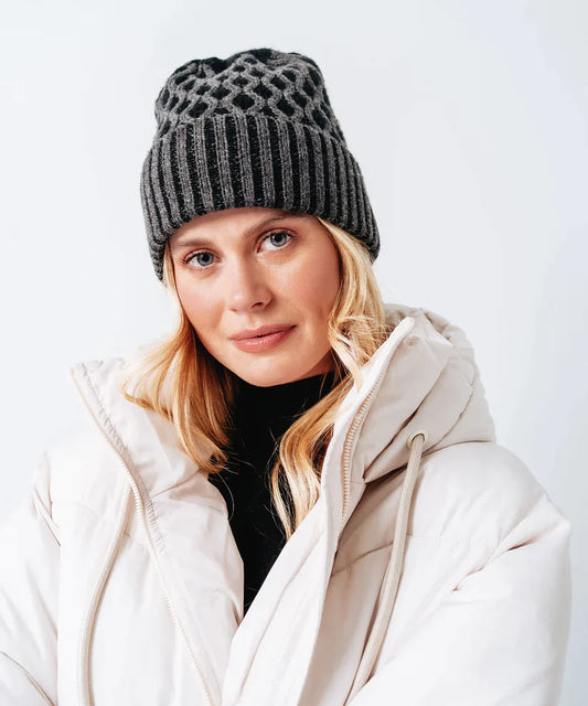 A woman wearing an Echo New York Recycled Bi-Color Honeycomb Beanie with ultra-soft lining and white jacket.
