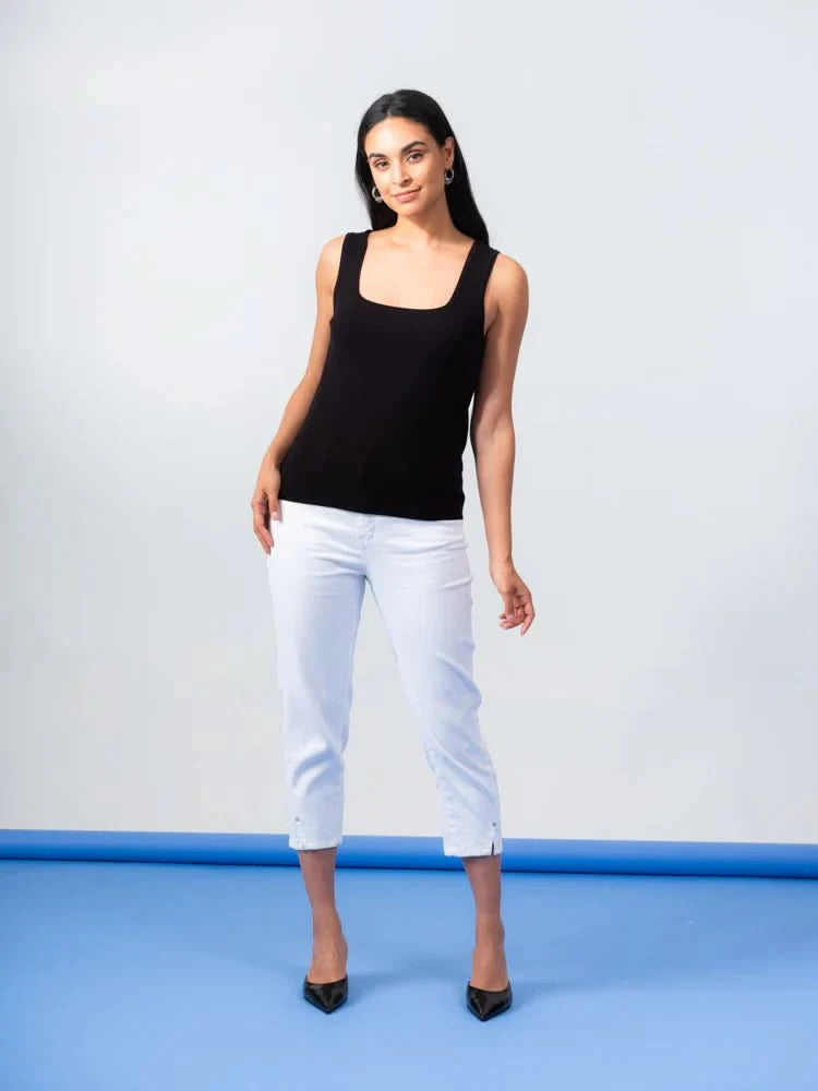 The person wears an Elena Wang Reversible Heavy Tank Top and black wide-leg pants with white heels. Posing against a blue-gray background, the fashionable top adds versatility as they look to the side.