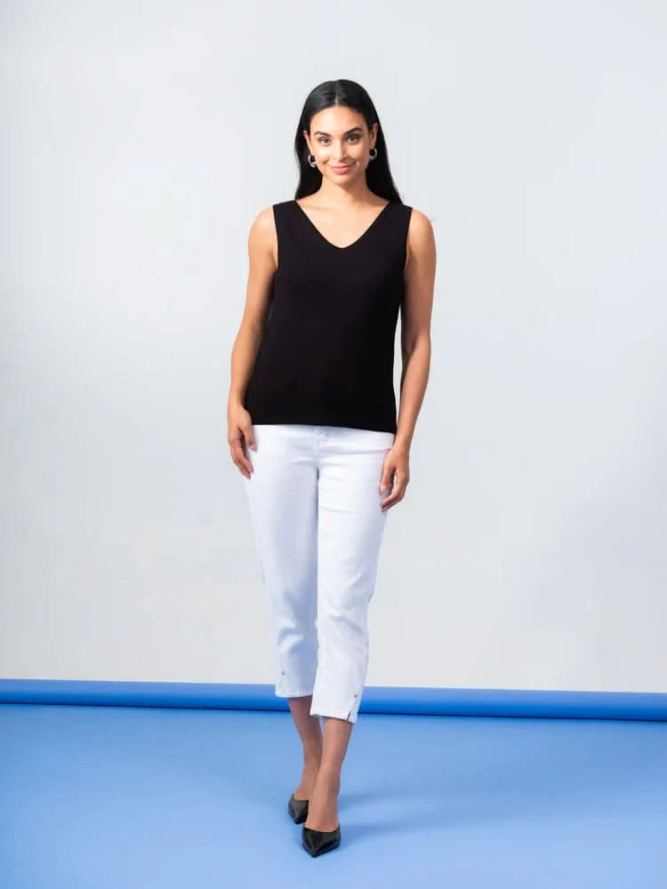 The person wears an Elena Wang Reversible Heavy Tank Top and black wide-leg pants with white heels. Posing against a blue-gray background, the fashionable top adds versatility as they look to the side.