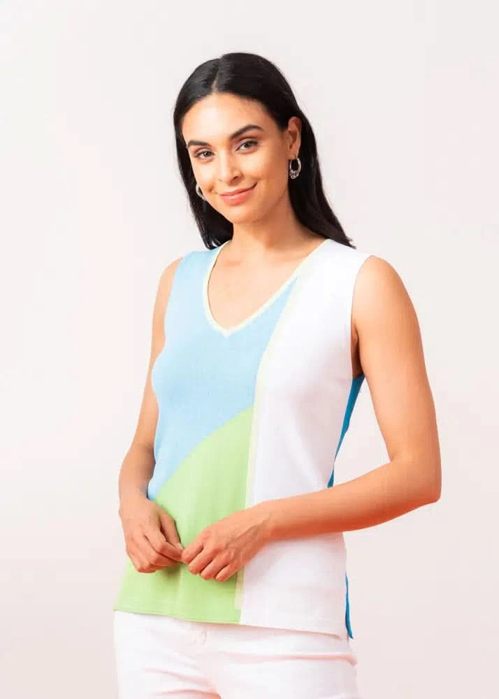 A woman poses on an orange surface, displaying a Multi Color Tank Top by Elena Wang with green, blue, and white sections. She pairs it with comfortable white capri pants and yellow sandals—perfect for everyday wear—set against a neutral background.