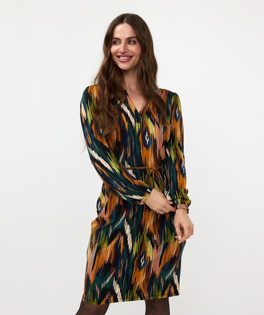 Wearing the versatile and stylish V-Neck Amazon Dress by Esqualo, this person pairs the vibrant, multicolored patterned garment with classic brown boots against a clean white background.